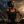 Woman in black tank top standing with hands on hips against a dramatic sky.