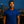 Man wearing a blue shirt standing against a city skyline at night.