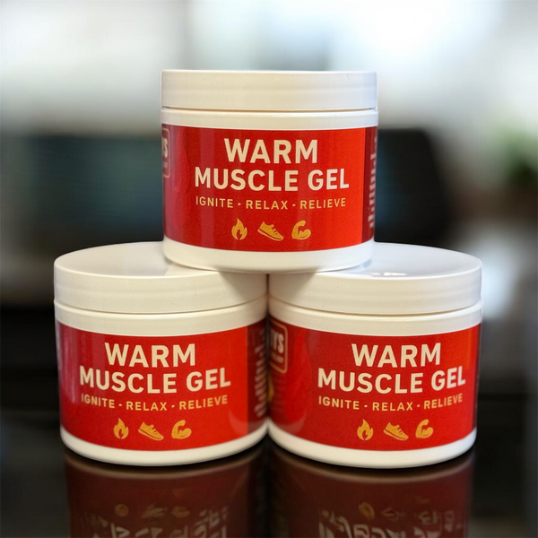 Three jars of warm muscle gel stacked on a reflective surface with a blurred background.